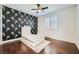 Bedroom with hardwood floors, large window with plantation shutters, accent wallpaper, and a twin sized bed at 5337 Polizze Ave, Las Vegas, NV 89141