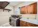 Laundry room featuring a utility sink, wooden cabinets, and modern washer and dryer units under hanging racks at 5337 Polizze Ave, Las Vegas, NV 89141