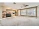Spacious living room featuring a fireplace, modern ceiling fan, and plenty of natural light from large windows at 5337 Polizze Ave, Las Vegas, NV 89141