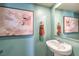 Modern half bath features a pedestal sink, contemporary fixtures, and stylish decorative artwork at 6157 Aster Garden St # 153, North Las Vegas, NV 89081