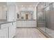 Modern bathroom with dual sinks, white cabinets, and a spacious walk-in shower with gray tiling at 6545 Vanhoven Crest St, Las Vegas, NV 89166