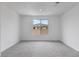 Unfurnished bedroom featuring light gray carpet, neutral walls, and a view of the neighboring roof at 6545 Vanhoven Crest St, Las Vegas, NV 89166
