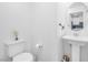 Powder room showcasing a pedestal sink, toilet, and decor with view of kitchen through a mirror at 7364 N Decatur Blvd # 4, Las Vegas, NV 89131