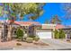 Charming home featuring a white garage door, mature landscaping, and a tile roof under a blue sky at 8552 Desert Holly Dr, Las Vegas, NV 89134