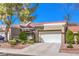 Charming home featuring a white garage door, mature landscaping, and a tile roof under a blue sky at 8552 Desert Holly Dr, Las Vegas, NV 89134