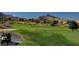Scenic golf course view with lush green fairways, mature trees, and a golf cart, set against a backdrop of mountains at 8552 Desert Holly Dr, Las Vegas, NV 89134