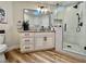 A modern bathroom features a granite vanity, walk-in shower, and wood-style floors at 8913 Saint Pierre Dr, Las Vegas, NV 89134