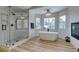 A modern bathroom features a luxurious soaking tub, walk-in shower, fireplace and natural light at 8913 Saint Pierre Dr, Las Vegas, NV 89134
