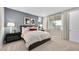 This primary bedroom boasts a queen bed, neutral carpet, a blue accent wall, and natural light from a window at 91 Tardando Ave, Henderson, NV 89015