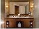 Bathroom vanity with dual sinks, decorative mirror, sconce lighting, and storage underneath at 2000 N Fashion Show Dr # 4302, Las Vegas, NV 89109