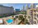 View from condo balcony of pool, tennis courts, and driving range surrounded by palm trees and buildings at 205 E Harmon Ave # 1007, Las Vegas, NV 89169