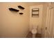 Small bathroom with mounted shelves, toilet, and a white door at 386 Espressivo St, Henderson, NV 89011