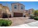 Two-story home with a dark wood garage door, brick driveway and mature landscaping at 386 Espressivo St, Henderson, NV 89011