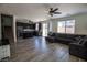 Open-concept living room features wood tile floors, ceiling fan, and gray sofa with a kitchen view at 386 Espressivo St, Henderson, NV 89011