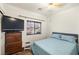 Comfortable bedroom with a plush blue bed, wooden dresser, and natural light from the window at 4429 S Glory Vine Ln, Pahrump, NV 89061