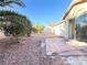 Spacious backyard with desert landscaping, a stone patio, and a mature shade tree at 5829 Aqua Verde St, North Las Vegas, NV 89031