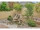 Backyard waterfall feature surrounded by lush greenery and decorative rocks, creating a peaceful ambiance at 5835 Farmhouse Ct, Las Vegas, NV 89141