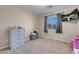 Comfortable bedroom with neutral walls, window, carpeting, and a TV for relaxation and entertainment at 6461 Karlsen Ct, Las Vegas, NV 89122