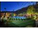 Backyard with a pool, artificial turf, privacy landscaping, lounge chairs, and night lighting at 6491 Wild Blue Ct, Las Vegas, NV 89135