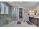 Bathroom boasts a glass shower, a double vanity with elegant lighting, and wood-look tile flooring at 6491 Wild Blue Ct, Las Vegas, NV 89135