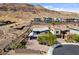 View of the home with a two car garage nestled at the base of the mountains at 6491 Wild Blue Ct, Las Vegas, NV 89135