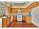 A kitchen featuring wood cabinets, laminate countertops, a white stove, and wood-look flooring at 7054 Burcot Ave # G40, Las Vegas, NV 89156