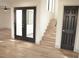 Hallway featuring hardwood floors, black framed glass doors and access to a staircase and closet at 8101 Spur Ct, Las Vegas, NV 89145