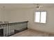 Bright loft area with a dark railing, ceiling fan and large window offering a view of downstairs at 8101 Spur Ct, Las Vegas, NV 89145
