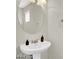 Pedestal sink in a half bath features a round mirror and modern fixtures at 9050 W Tropicana Ave # 1009, Las Vegas, NV 89147