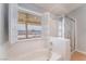 Bright bathroom featuring a shower, large tub, and a view to the backyard at 1010 Armillaria St, Henderson, NV 89011
