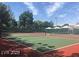 Well-maintained tennis court with green and red surface, surrounded by lush greenery at 1403 Bareback Ct, Henderson, NV 89014