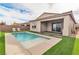 Backyard pool with two lounge chairs, artificial grass and covered patio near sliding glass doors at 154 Nine Mile Creek Dr, Las Vegas, NV 89138