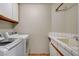 Bright laundry room with white cabinets, sink, and modern appliances at 2073 Sapphire Valley Ave, Henderson, NV 89074