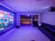 A modern living room with colorful lighting, a large screen, comfortable sofa, and sliding glass doors to an outdoor patio at 270 Shaded Canyon Dr, Henderson, NV 89012