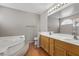 Bright bathroom features a soaking tub, double sink vanity, and wood-look flooring at 2716 Timber Crossing Ct, Henderson, NV 89074