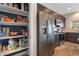 Spacious pantry next to a stainless refrigerator, dark cabinets, granite countertops, and modern appliances in the kitchen at 6661 Gallup Ct, Pahrump, NV 89060