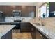 Granite countertops and stainless appliances add a modern touch to this kitchen with dark wood cabinets and lots of light at 6661 Gallup Ct, Pahrump, NV 89060