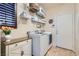 Well-lit laundry room with front-loading washer and dryer, storage shelves, and tiled floor at 7154 Brighton Village St, Las Vegas, NV 89166