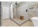 Walk-in shower with pebble floor, wood stool and stone tile surround in a modern bathroom at 8220 Tursi Lodge Ct, Las Vegas, NV 89131