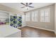 Bedroom features built-in shelves, wood floors, bright windows, and a ceiling fan with light at 8220 Tursi Lodge Ct, Las Vegas, NV 89131