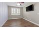 Bright bedroom featuring hardwood floors, shuttered windows, ceiling fan, and a mounted television at 8220 Tursi Lodge Ct, Las Vegas, NV 89131
