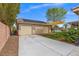 Two-car garage featuring a wide driveway, solar panels and adjacent yard at 8220 Tursi Lodge Ct, Las Vegas, NV 89131