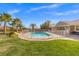 Backyard pool enclosed by fence with palm trees, grassy lawn, and blue skies at 8220 Tursi Lodge Ct, Las Vegas, NV 89131