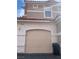 Beige attached one car garage of a two-story stucco home under a red tile roof in a sunny neighborhood at 8555 W Russell Rd # 1078, Las Vegas, NV 89113