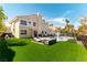 Home's backyard featuring an outdoor pool, seating, lush artificial grass, and privacy fencing at 8816 Saint Pierre Dr, Las Vegas, NV 89134
