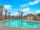 Community pool surrounded by palm trees, featuring a bath house and lounge chairs at 9315 Indian Corn Ct # 101, Las Vegas, NV 89178
