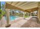 Covered patio overlooks a backyard pool area enclosed by a fence and lush greenery at 9733 Camden Hills Ave, Las Vegas, NV 89145