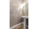 Bathroom featuring a pedestal sink, vanity mirror, decorative sconce lighting, and unique wall textures at 12169 Castilla Rain Ave, Las Vegas, NV 89138