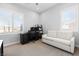 Bright bedroom with large windows, a black desk, and a white loveseat for relaxation or work at 12169 Castilla Rain Ave, Las Vegas, NV 89138