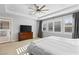 Bedroom featuring a ceiling fan, an exterior door, plantation shutters, and a large TV on a wood dresser at 12169 Castilla Rain Ave, Las Vegas, NV 89138